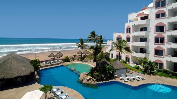 Un resort con piscina, playa y vista al océano.
