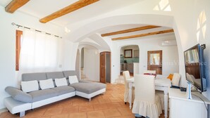 Un salón amplio con un sofá seccional, una mesa de comedor y un televisor.