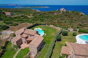 A villa with a swimming pool, surrounded by lush greenery and a view of the sea.