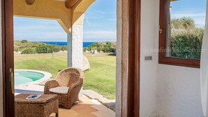 Una habitación con vista al mar, una silla de mimbre y una piscina pequeña.