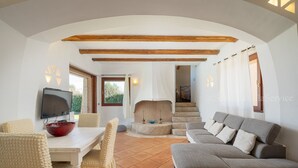 Un salón amplio con una mesa blanca, sillas color beige, un sofá gris y una chimenea.