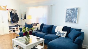 A living room with a blue sofa, a white coffee table, and a vase with flowers.