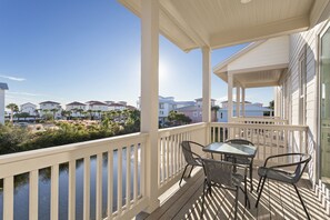 Enjoy a serene outdoor space with a deck, table, and chairs overlooking a body of water and surrounding homes.
