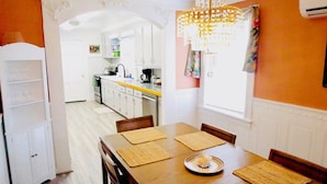 Una sala da pranzo con tavolo in legno, quattro sedie e un lampadario.