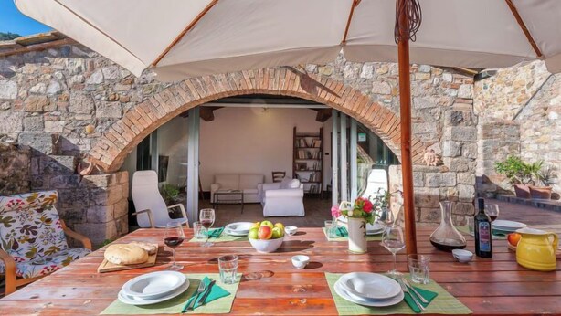 A dining area with a stone archway, wooden table, and outdoor seating. - Podere Vignali by Interhome (Pari)