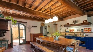A rustic kitchen with wooden beams, a wooden dining table, and blue cabinets. - Podere Vignali by Interhome (Pari)