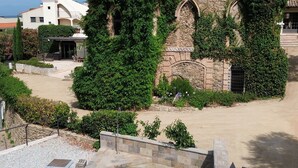 A stone building with ivy, a clear pool, and a white building in the background. - Mas Cusi (Palau-Saverdera)