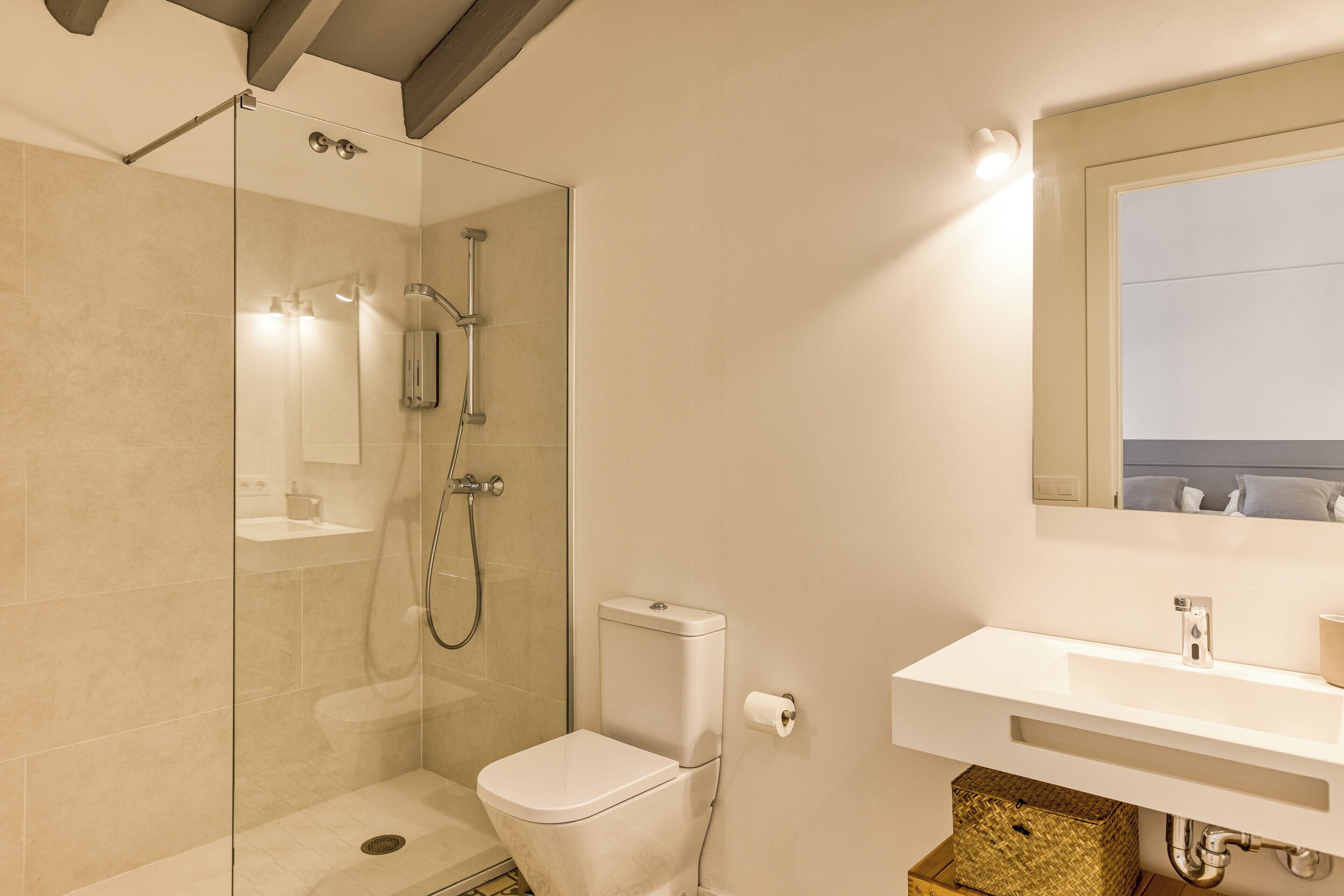A modern bathroom with a glass-enclosed shower, a white toilet, and a sink with a mirror above it.