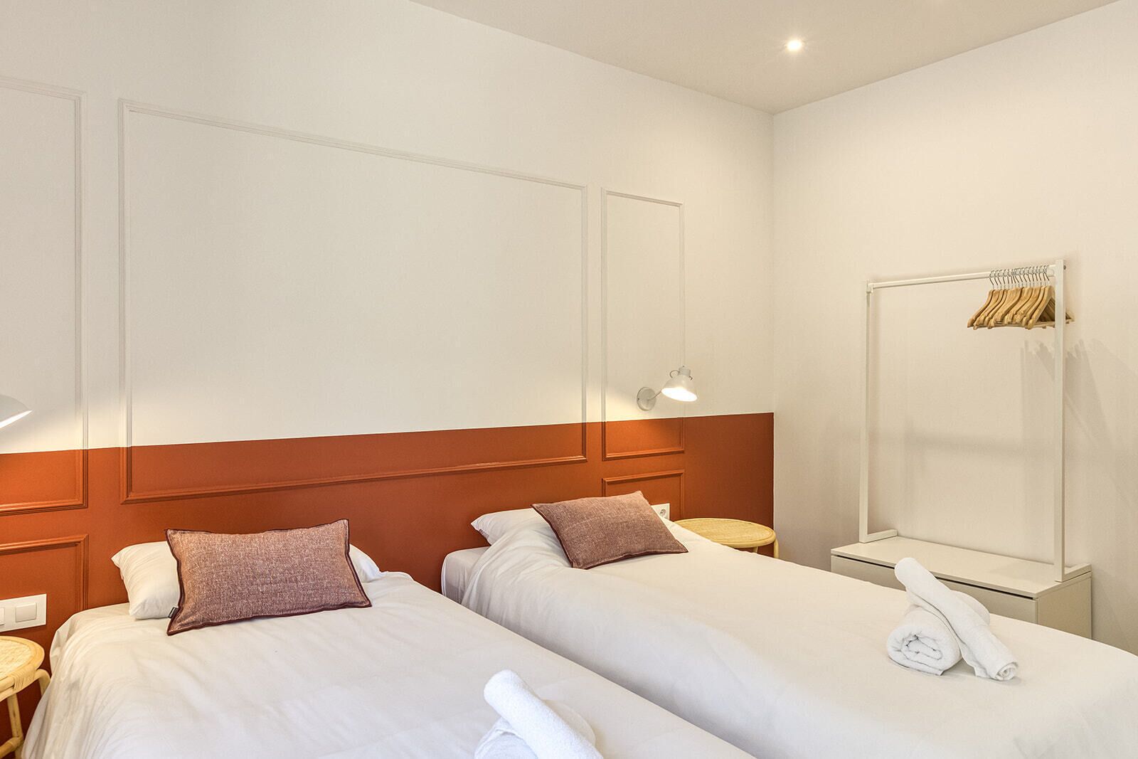 Een hotelkamer met twee bedden, een nachtkastje met een lamp, een spiegel en een handdoek op het bed.