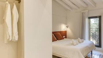 Un dormitorio con cama, cabecero de madera, ventana con vistas y suelo estampado.