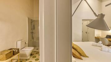 Habitación de hotel con ducha, inodoro, cama con almohadas y escritorio con una computadora portátil.