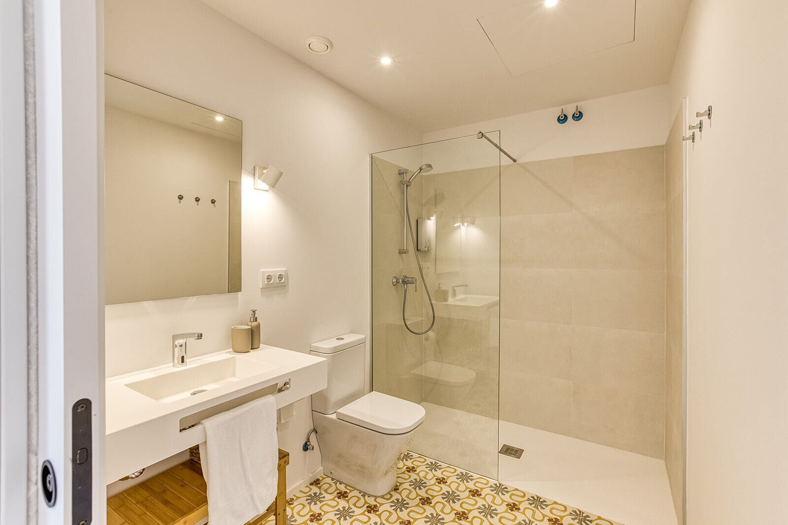 A modern bathroom with a glass-enclosed shower, a white sink, and a large mirror.