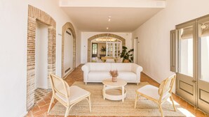 A spacious living area with a white sofa, two wicker chairs, a round coffee table, and a large window. - Mas Cusi (Palau-Saverdera)