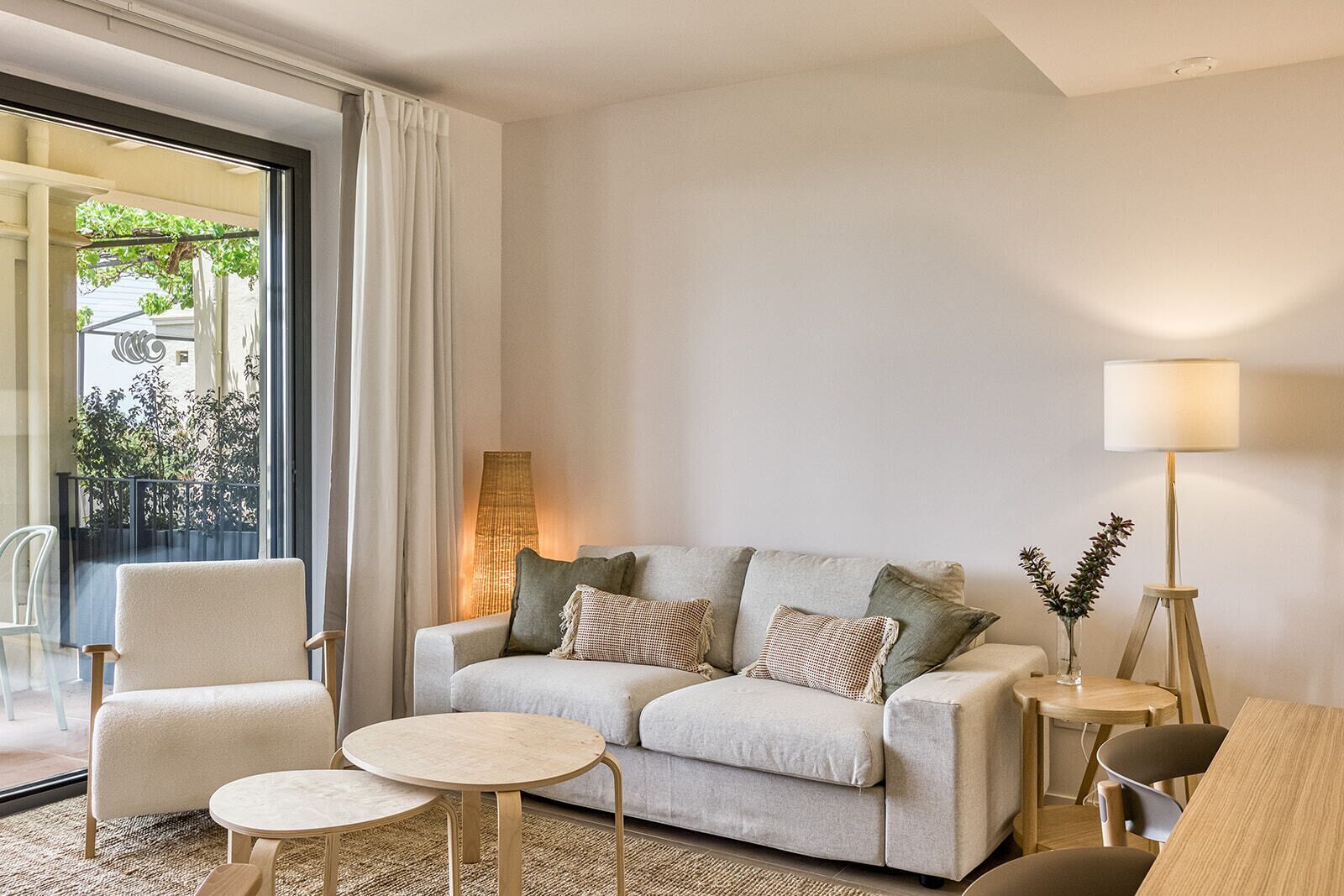 Ein modernes Wohnzimmer mit einer Couch, zwei Sesseln, einem Couchtisch und einer Lampe.