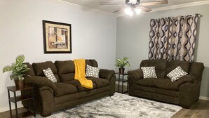 A living room with two brown sofas, a patterned rug, a ceiling fan, and a framed picture on the wall. - Charming Lafayette Condo: Cozy Retreat in Indiana (Lafayette)