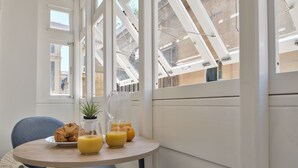 Een ontbijttafel met croissants, sinaasappelsap en een plant in pot.