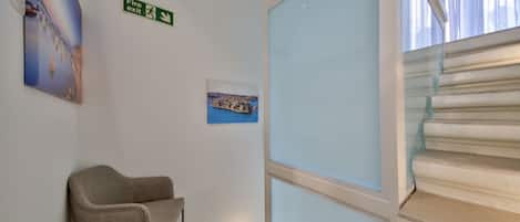 Una escalera con un cartel de salida de incendios, un cuadro enmarcado y una silla.
