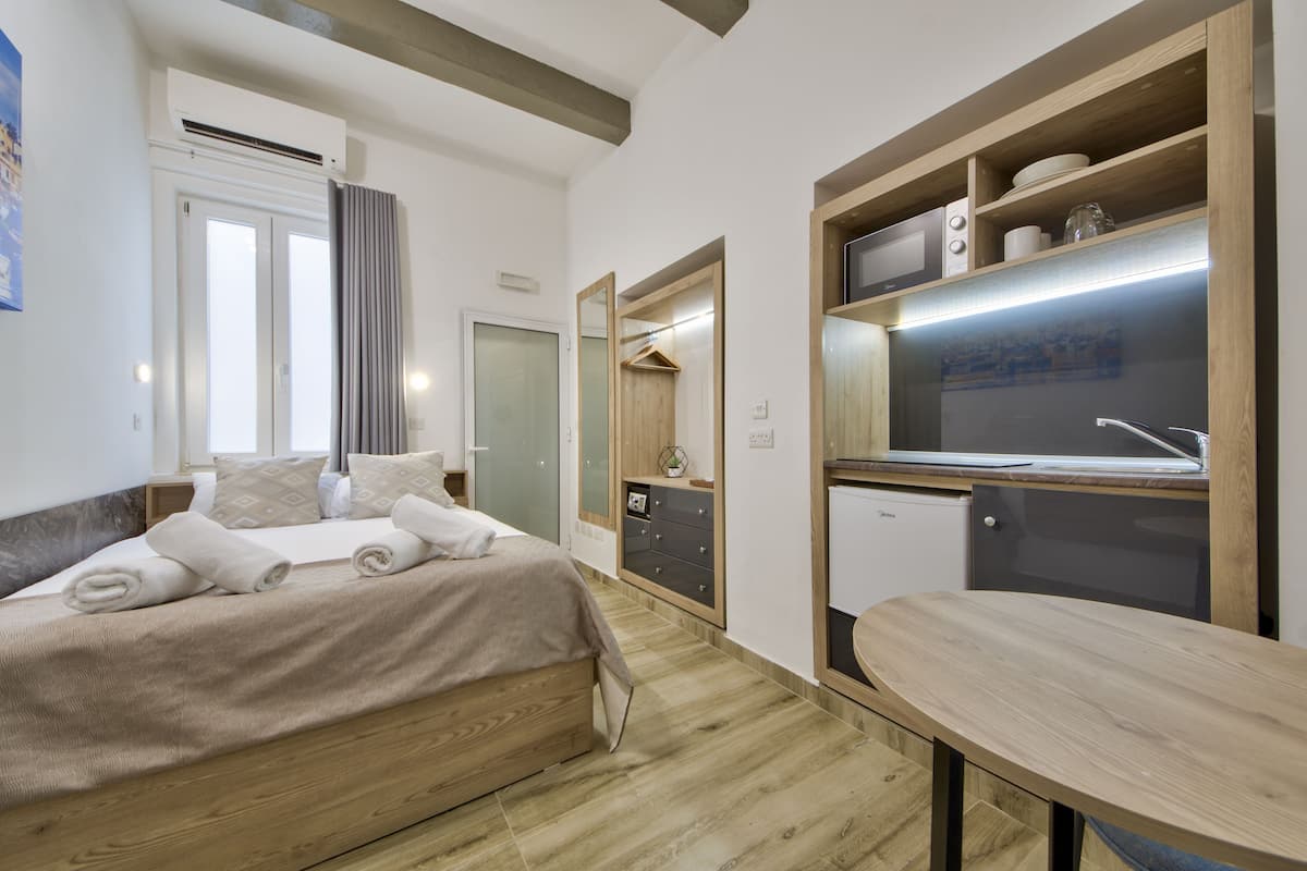 Een moderne hotelkamer met een houten bed, een kleine kitchenette en een eettafel.