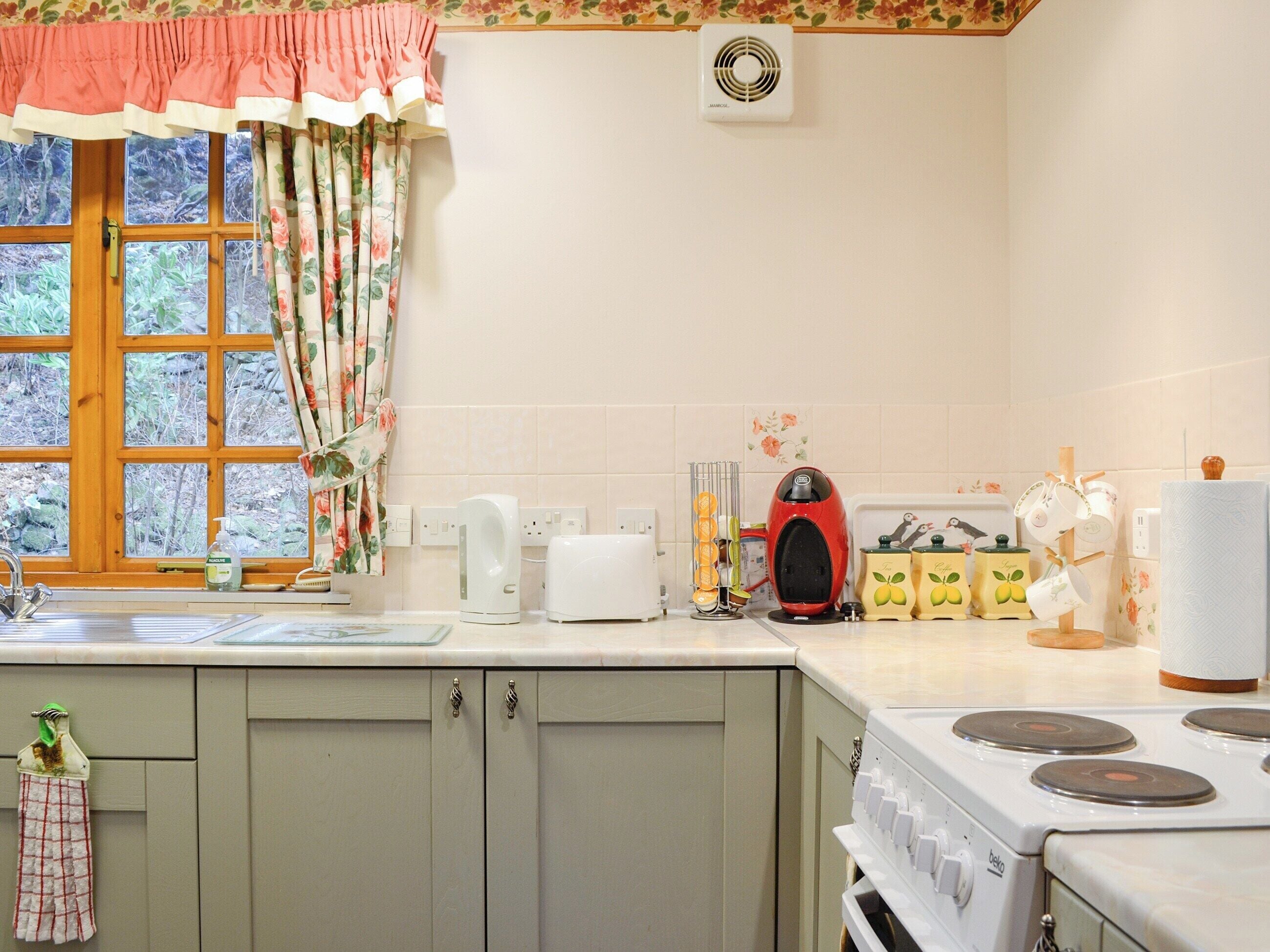 A kitchen with a window, a kettle, a toaster, and a stove.