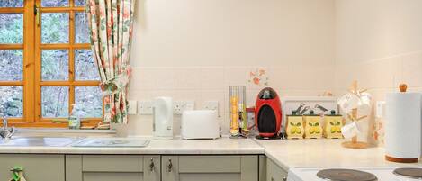 A kitchen with a window, a kettle, a toaster, and a stove.