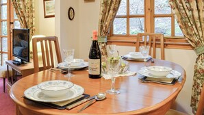 Une table à manger dressée avec des assiettes, des verres, une bouteille de vin et des couverts.