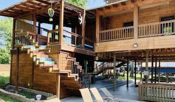 A wooden multi-level building with a balcony and outdoor seating area.