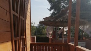 A wooden deck with a metal railing, a wooden gate, and a view of the surrounding area.