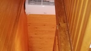 A small, enclosed wooden room with a white air conditioning unit mounted on the wall.