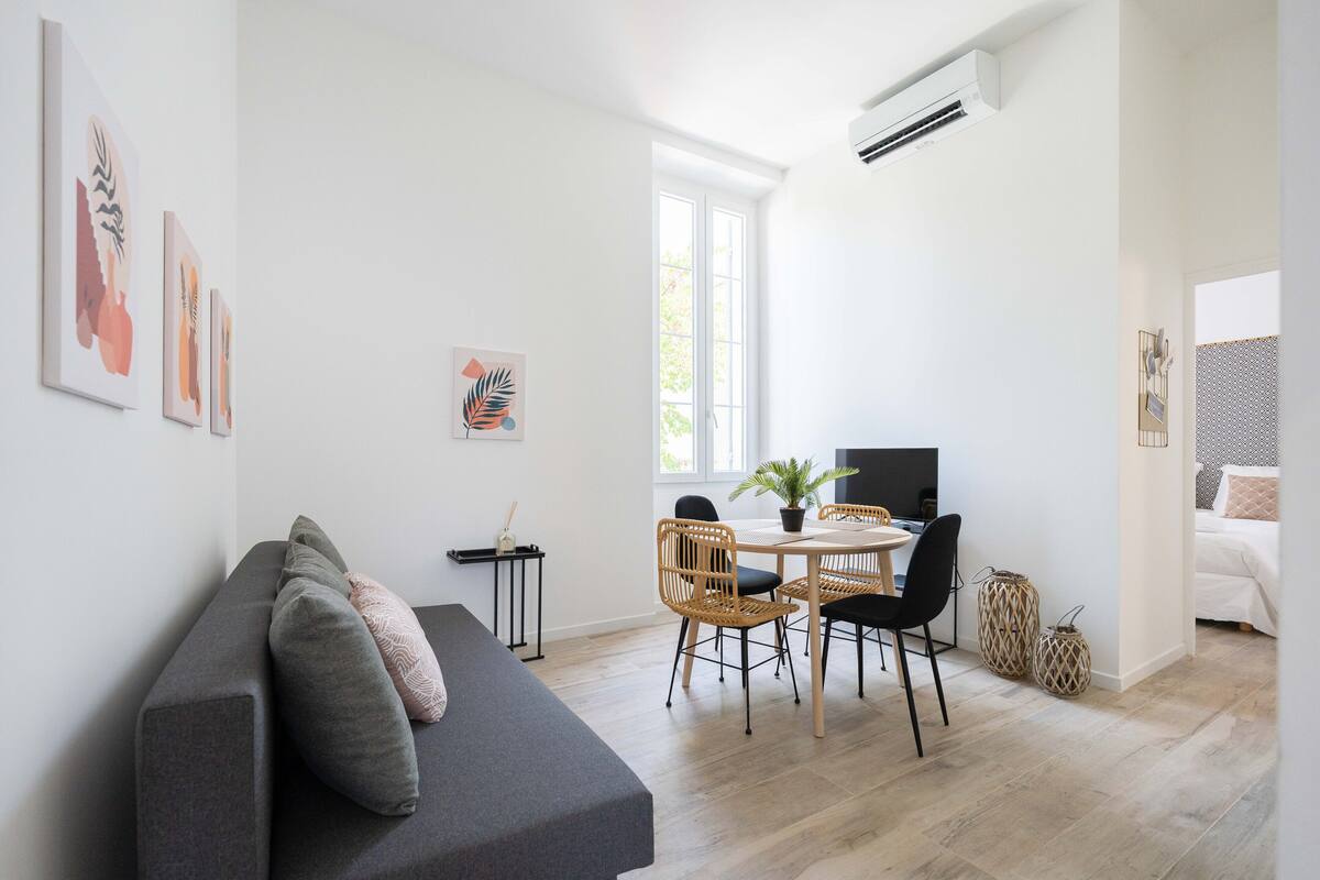 Una sala de estar moderna con sofá, mesa de comedor, sillas y obras de arte en las paredes.