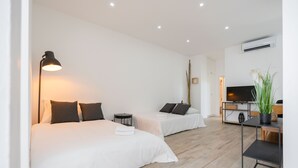 Ett hotellrum med två sängar, ett skrivbord, en tv och en växt.