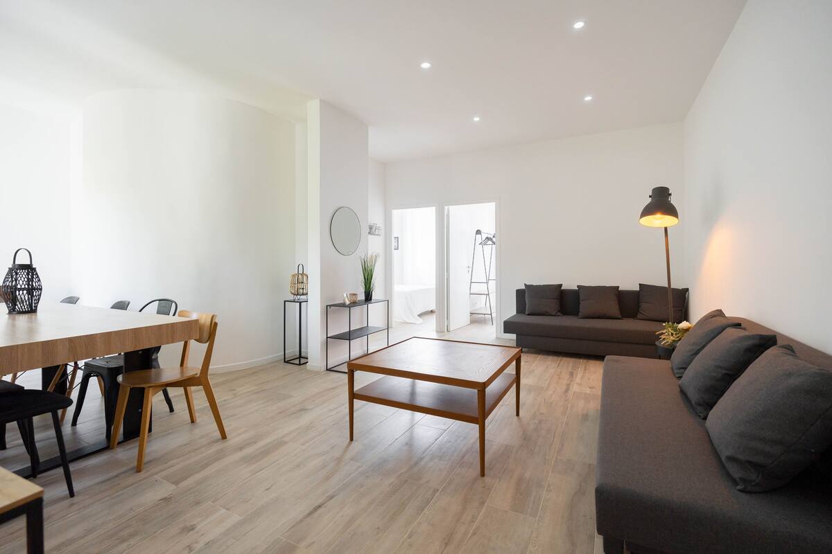 Una sala de estar moderna con una mesa de centro de madera, un sofá y un comedor con sillas.