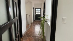 A hallway with a tiled floor, a black-framed door, and a potted plant.