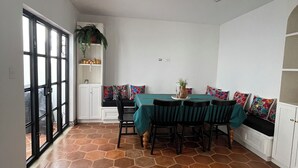 A dining area with a hexagonal tile floor, a table with chairs, and a bench with colorful cushions.