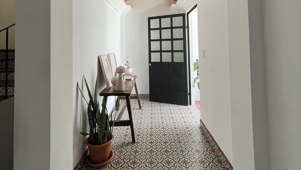 A hallway with patterned floor tiles, a brick ceiling, and a black door with glass panels.