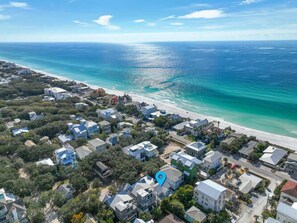 An aerial view of a coastal residential area with houses near the beach and a clear view of the ocean.