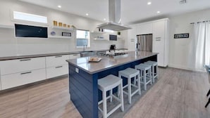 A modern kitchen with a central island, white cabinetry, and a stainless steel range hood. - Old Seagrove "Thyme by the Sea" |3BR| 2 Kings| Sleeps 9| 250ft from Beach! (Santa Rosa Beach)