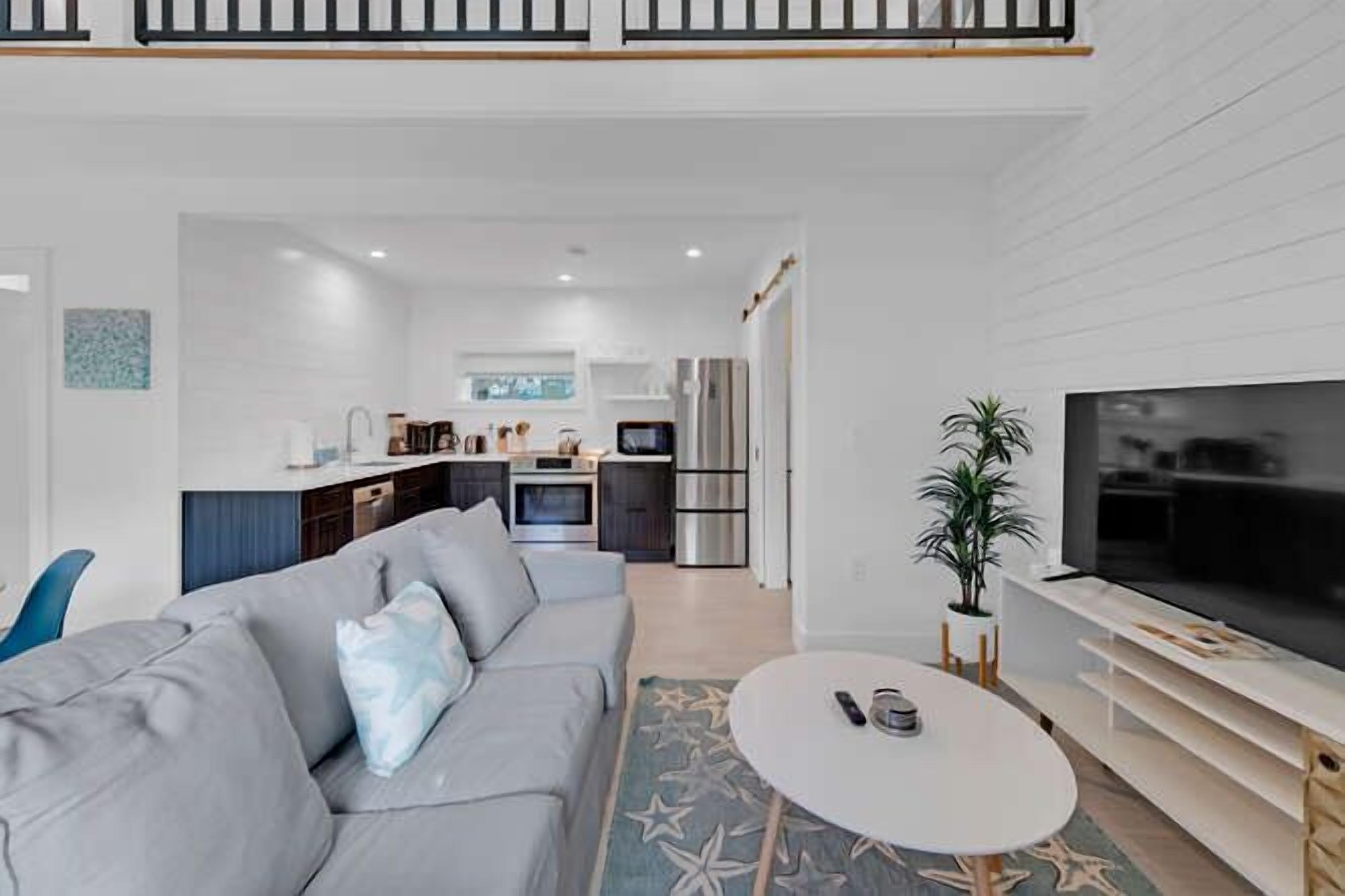 A modern living room with a grey sofa, a round coffee table, and a flat-screen TV.