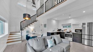 Ein modernes Interieur mit einem grauen Sofa, einer Treppe und einer Küchenzeile.