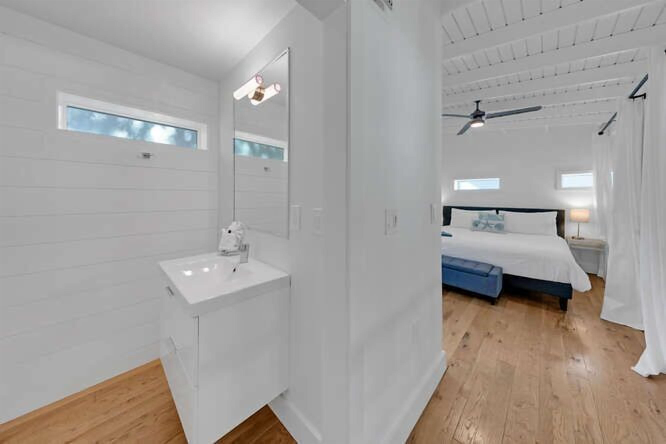 Quarto moderno com uma toucador branca, uma cama grande e um ventilador de teto.
