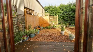 Un jardin agrémenté de plantes en pot, d’un banc en bois et d’une clôture en bois.