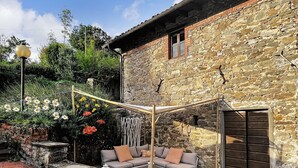 A stone building with a patio area featuring a white sofa and a pergola.