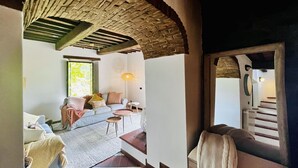 A cozy living area with a sofa, a small table, and a lamp. There is a staircase leading to another level.