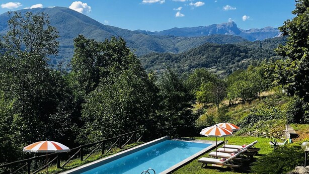 A rectangular swimming pool with a view of mountains in the background.