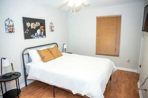 A bedroom with a bed, a nightstand, a lamp, and a window with blinds. - Spacious 3 bdrm Cincy home (Cincinnati)
