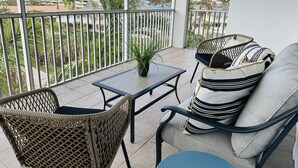 Un balcon agrémenté de meubles en osier, d’une petite table et d’une plante en pot.