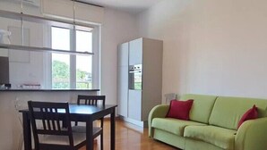 A compact living space with a dining area, a sofa, and a kitchenette.