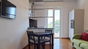 A compact living space with a dining area, kitchenette, and a green sofa.