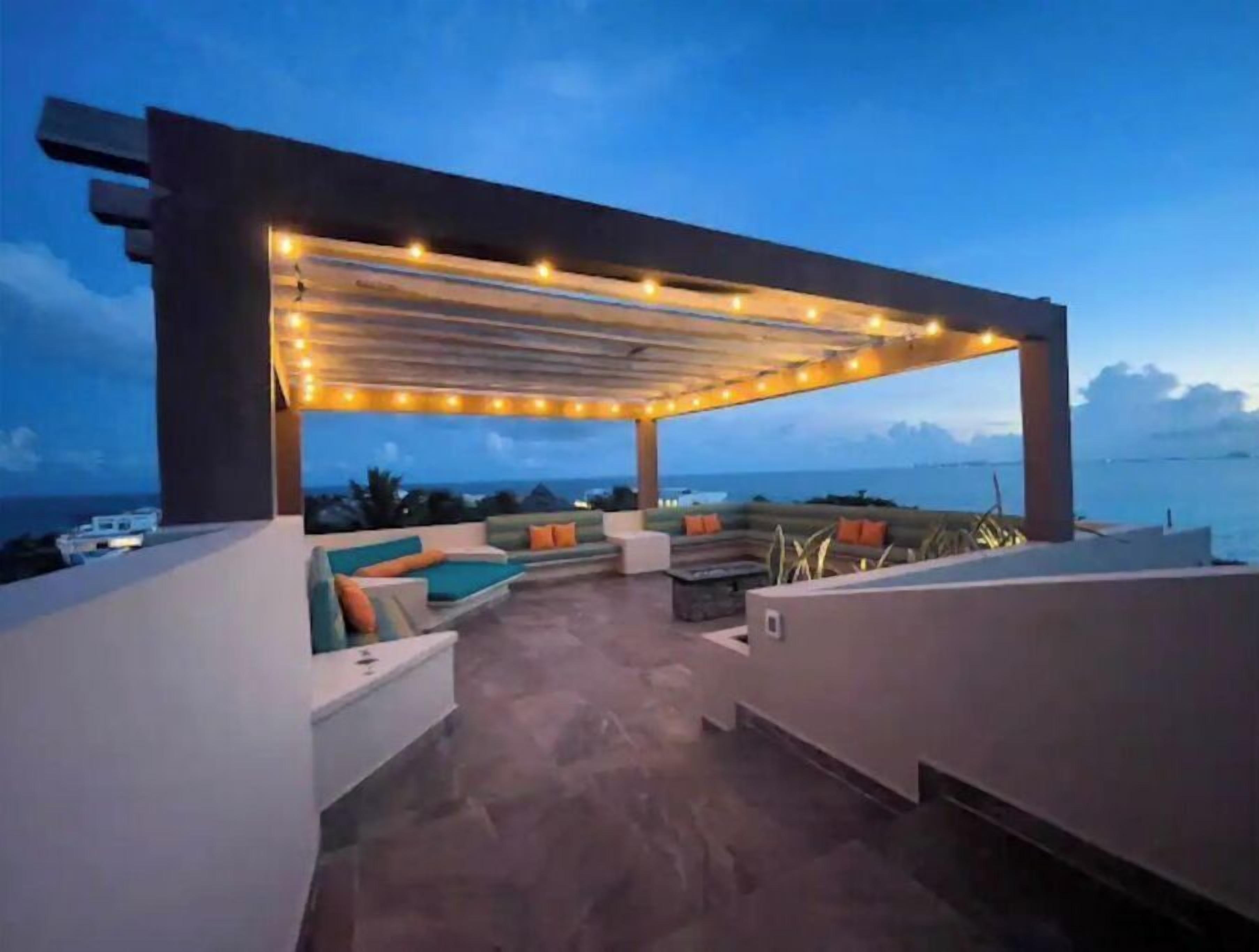 An outdoor seating area with a pergola, stone flooring, and a view of the sea.