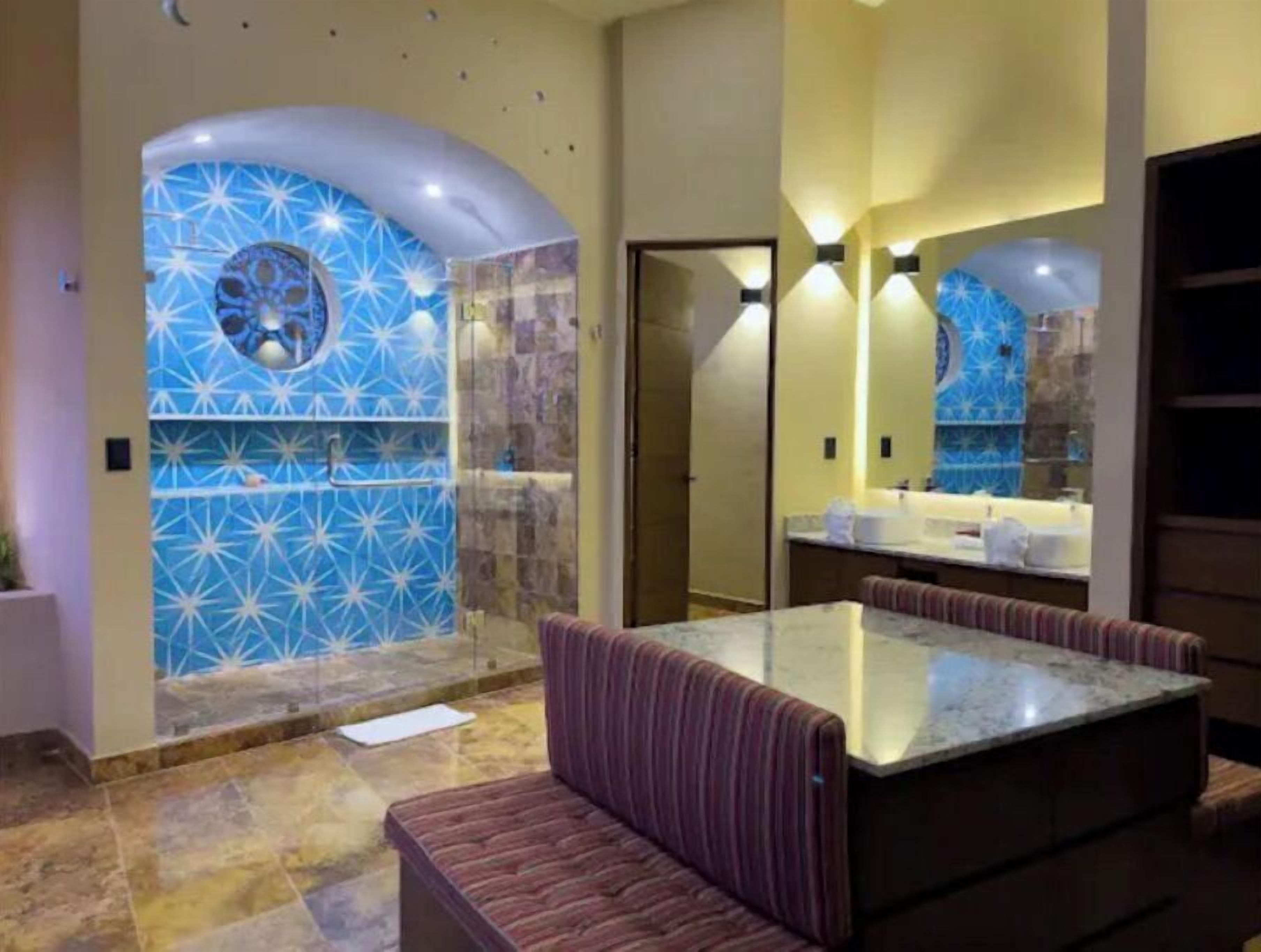 A bathroom with a blue star-patterned wall, a marble sink, and a bench.