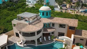 Una villa lujosa con una piscina central, varios balcones y una torre con forma de cúpula.